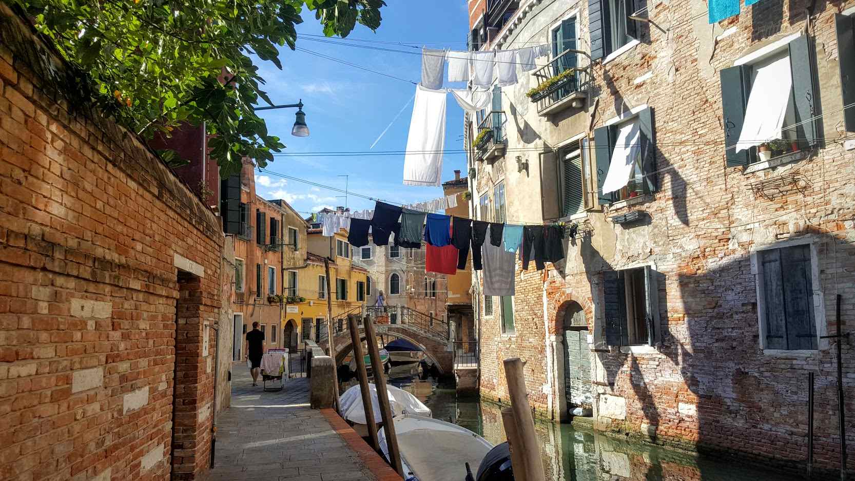 a street in venice with colourful clothes hanging to dry above a canal